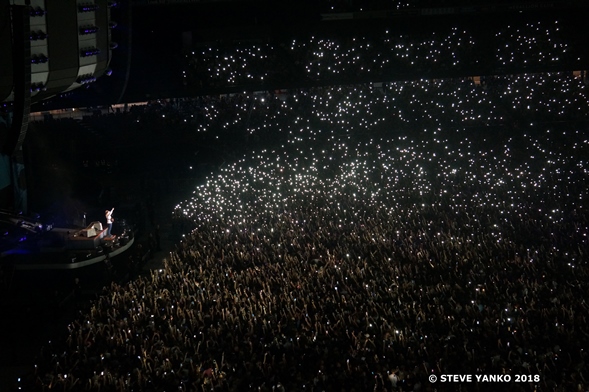 People  waving their mobile phone torches to Ed Sheeran.